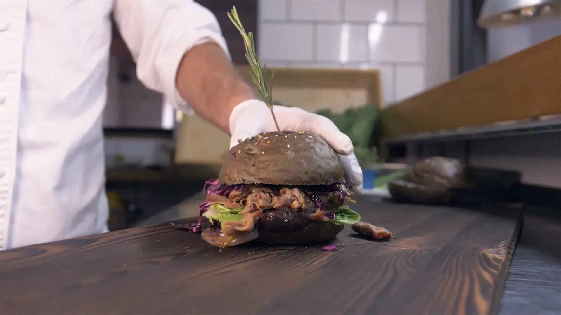 Kuchař kompletuje burger v kuchyni Tiskárny